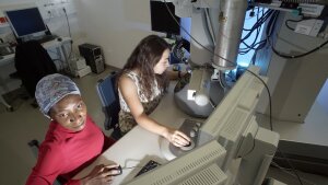 Zwei Chemikerinnen bei der Arbeit an einem Elektronenmikroskop.